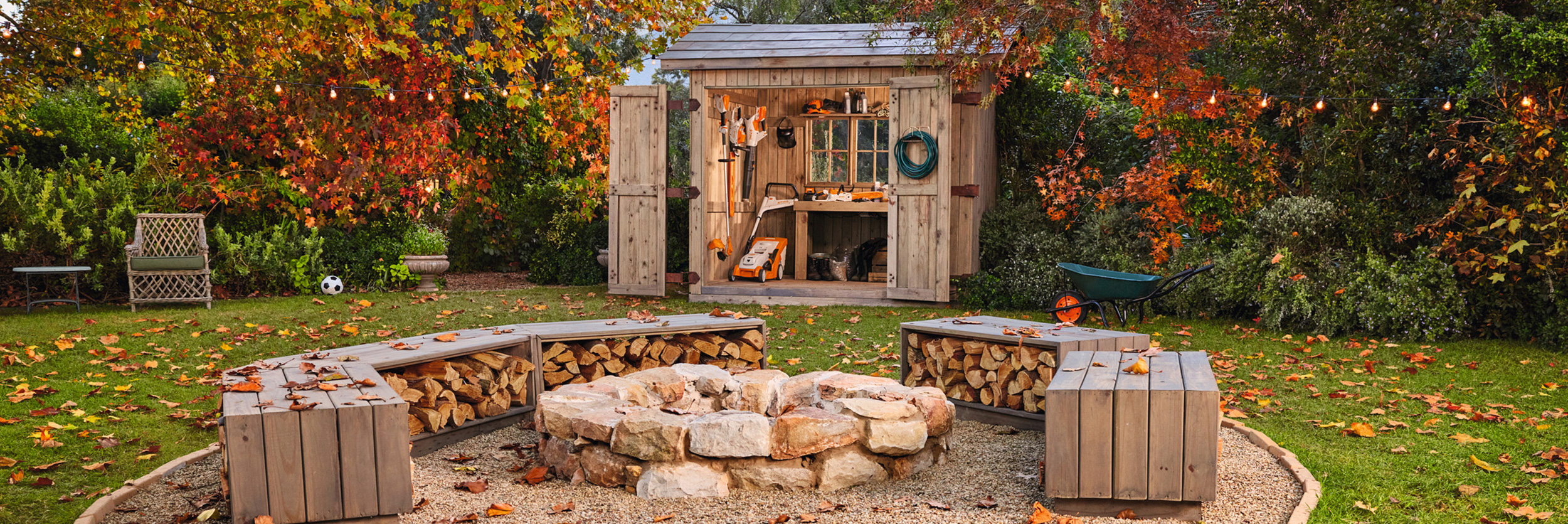 Jardin d’automne avec hangar rempli d’outils de jardinage STIHL et foyer de camp