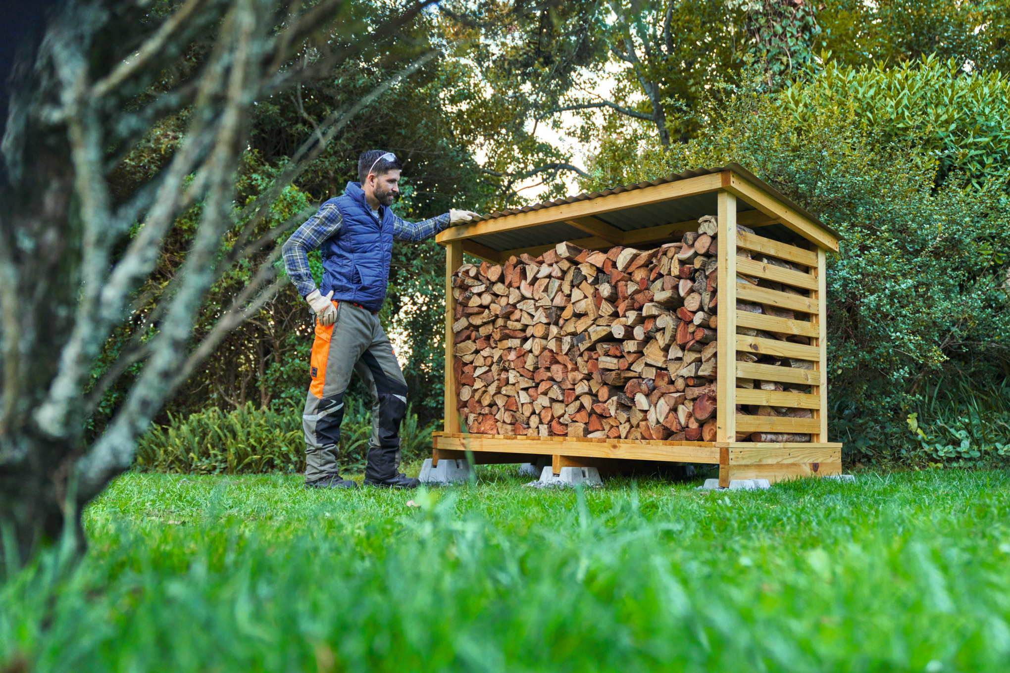 Homme en équipement de protection devant un abri à bois qu’il a construit lui-même