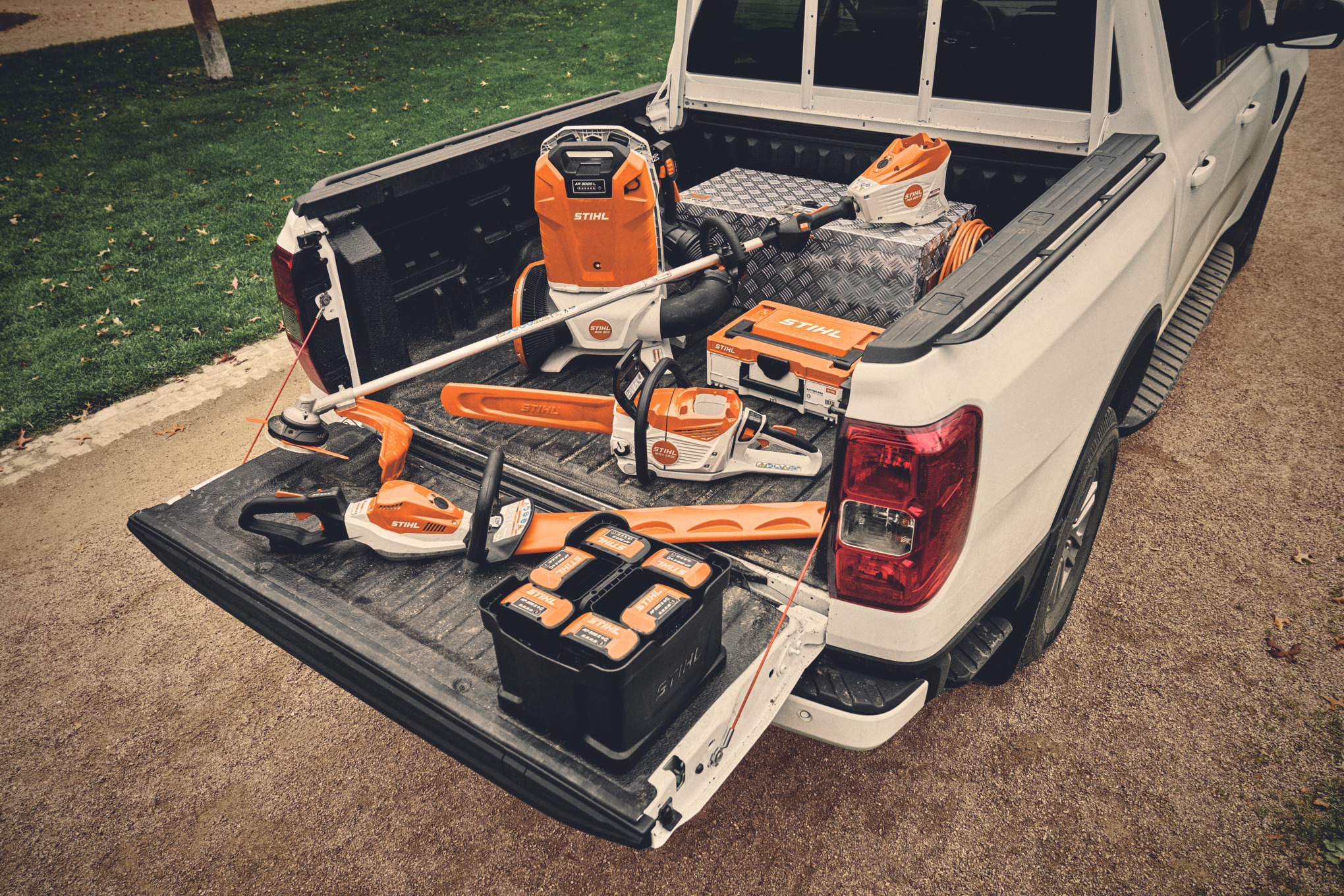 Différents appareils à batterie du système AP de STIHL et les batteries adaptées sur la surface de chargement d’un véhicule