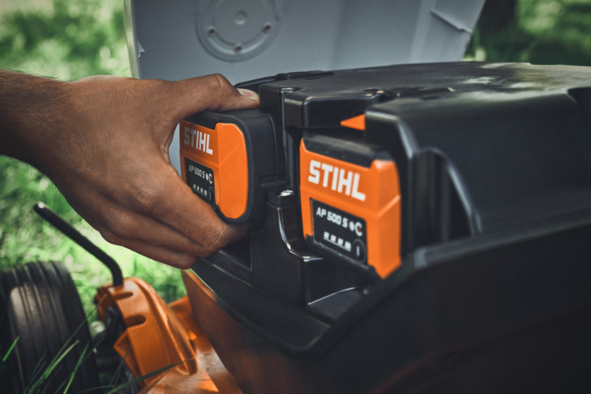 Une personne place une batterie AP 500 S STIHL dans une tondeuse à batterie STIHL