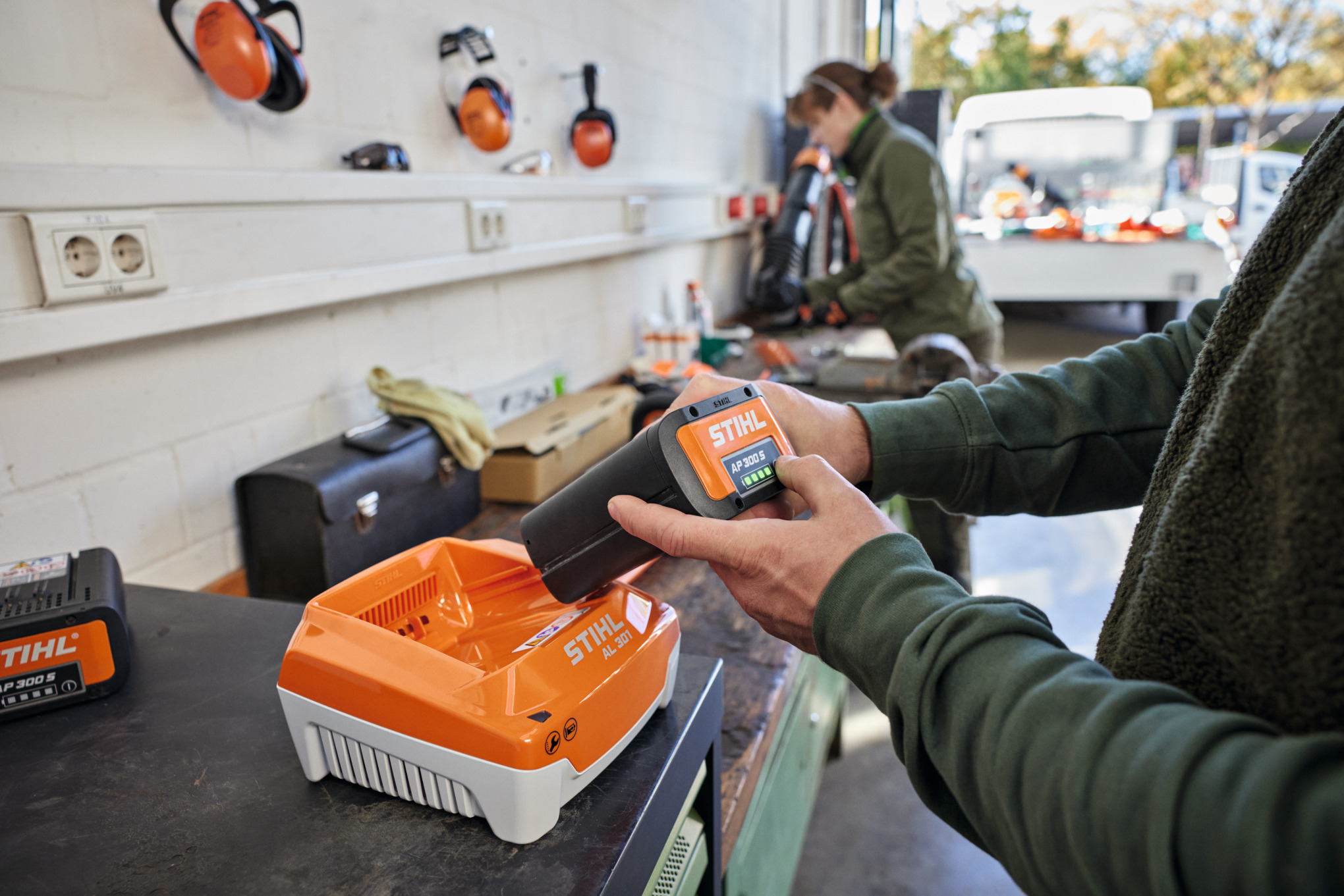 Une personne place une batterie STIHL AP 300 S dans un chargeur rapide STIHL AL 301