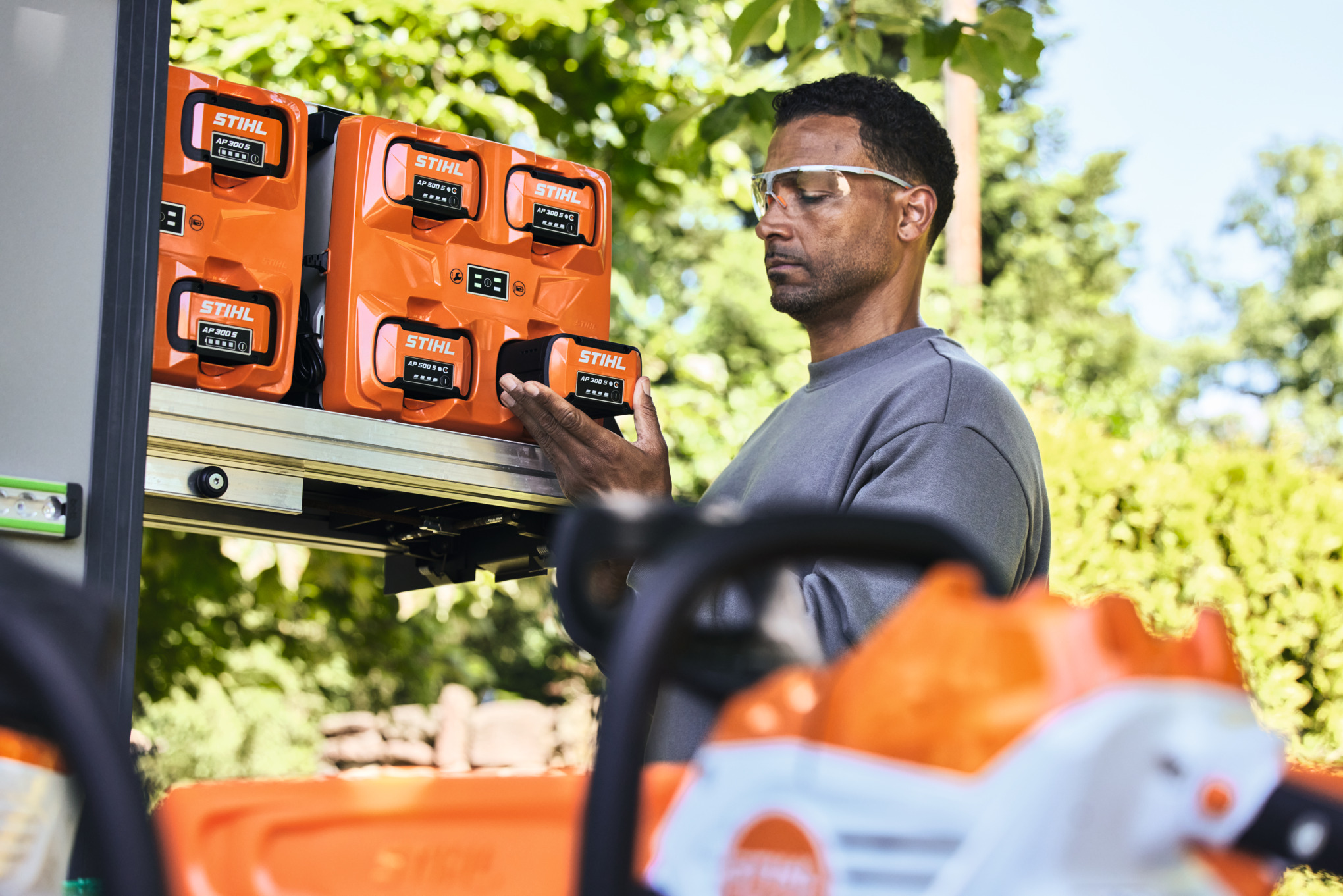 Un homme portant des lunettes de protection retire du bottTainer une batterie STIHL AP 300 S