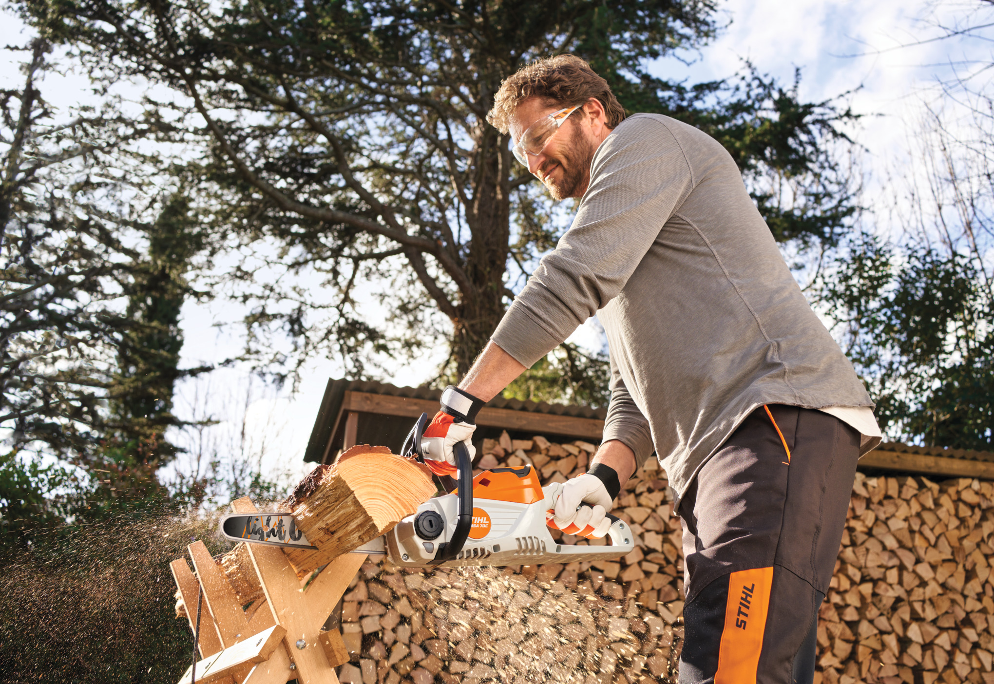 Homme coupant du bois avec une tronçonneuse STIHL sur un chevalet de sciage