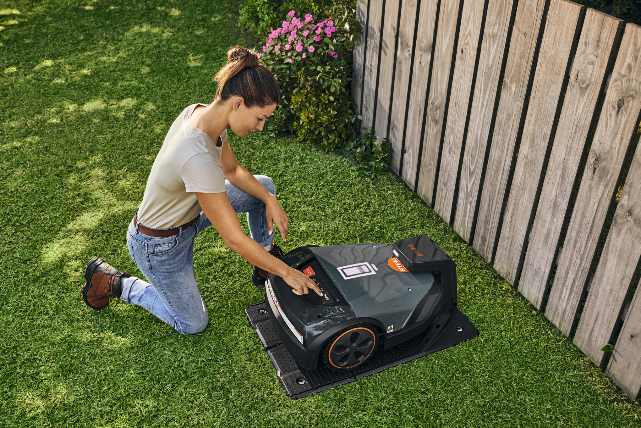 Tondeuse robot STIHL iMOW® sur la pelouse verte d’un jardin