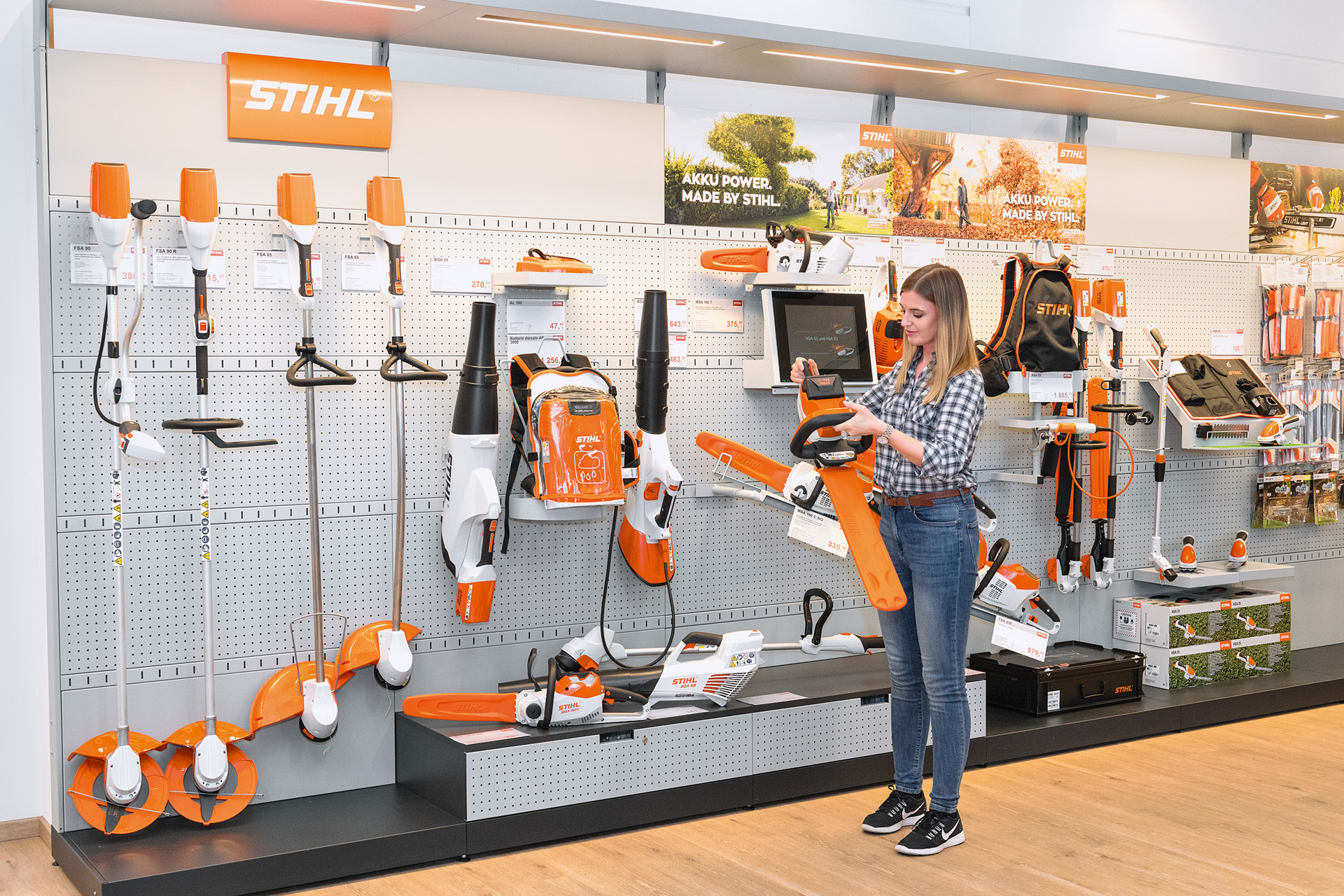 Une jeune femme devant un rayon de vente chez un revendeur STIHL veut tester gratuitement une tronçonneuse STIHL.