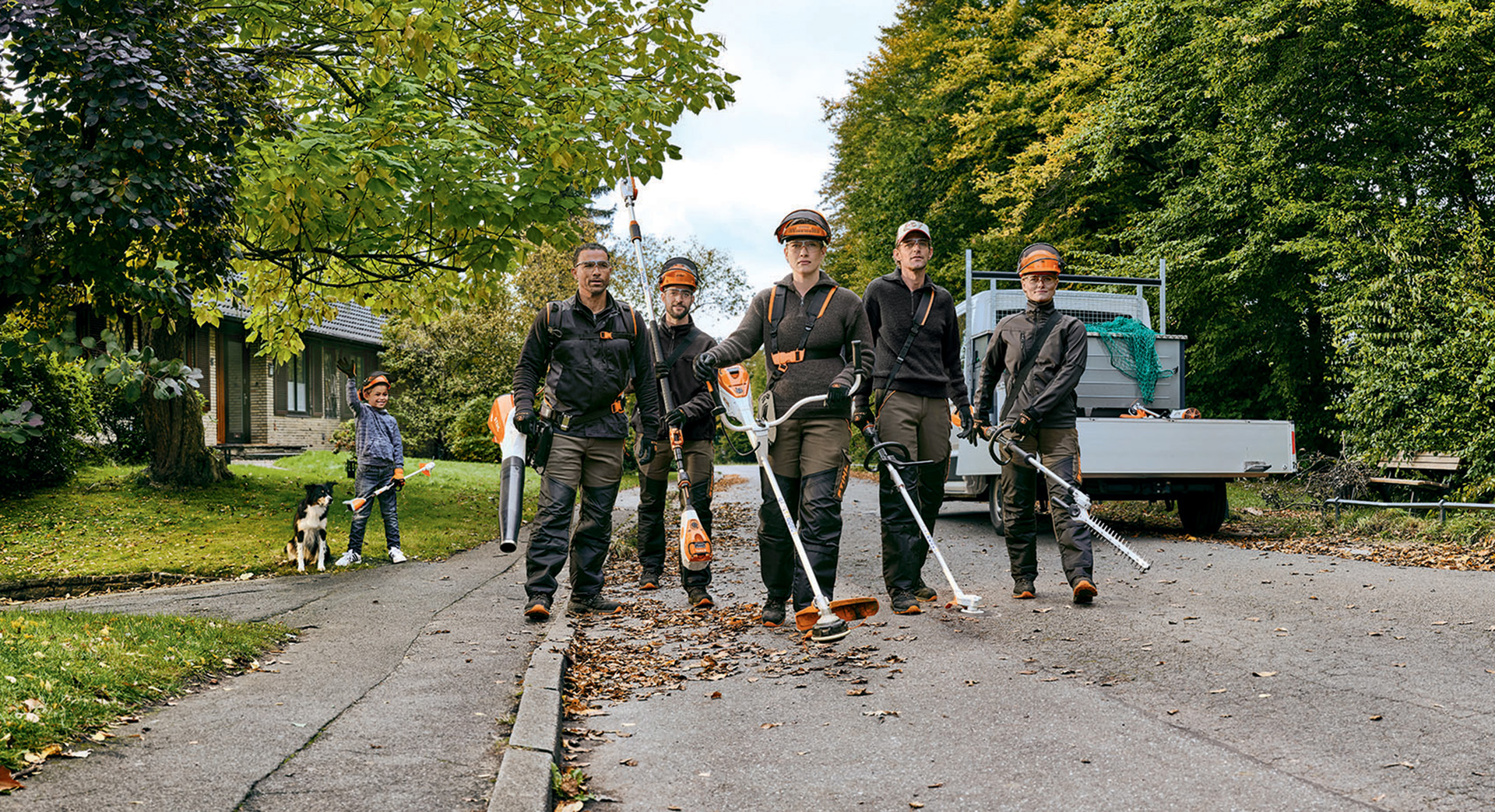 Une équipe de jardiniers et de paysagistes avec des outils à batterie professionnels de STIHL marchant dans une rue.
