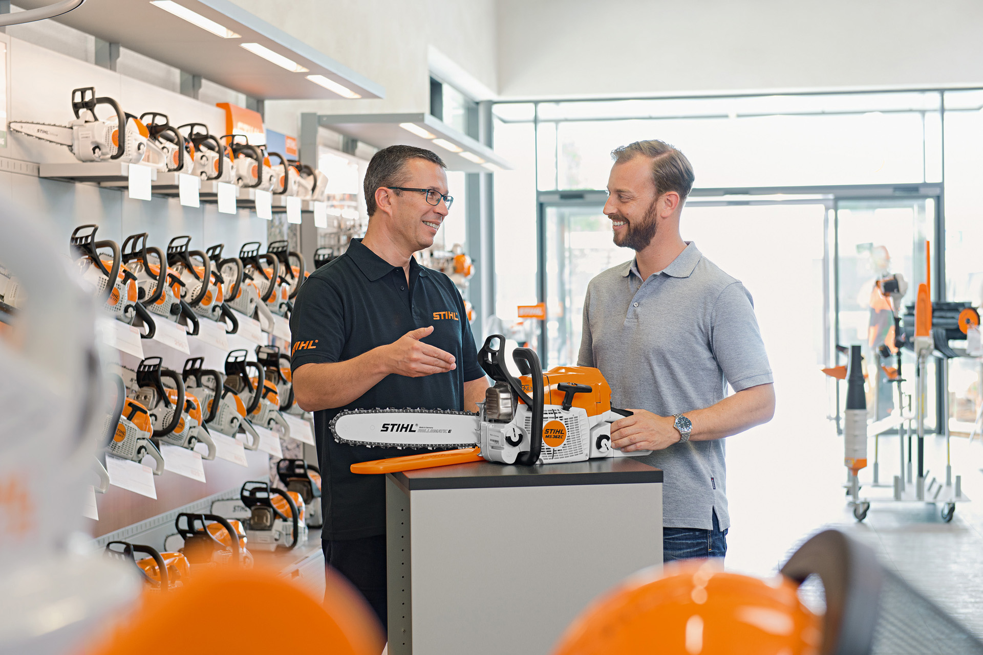 Un revendeur STIHL conseille un homme sur l'achat d'une tronçonneuse STIHL