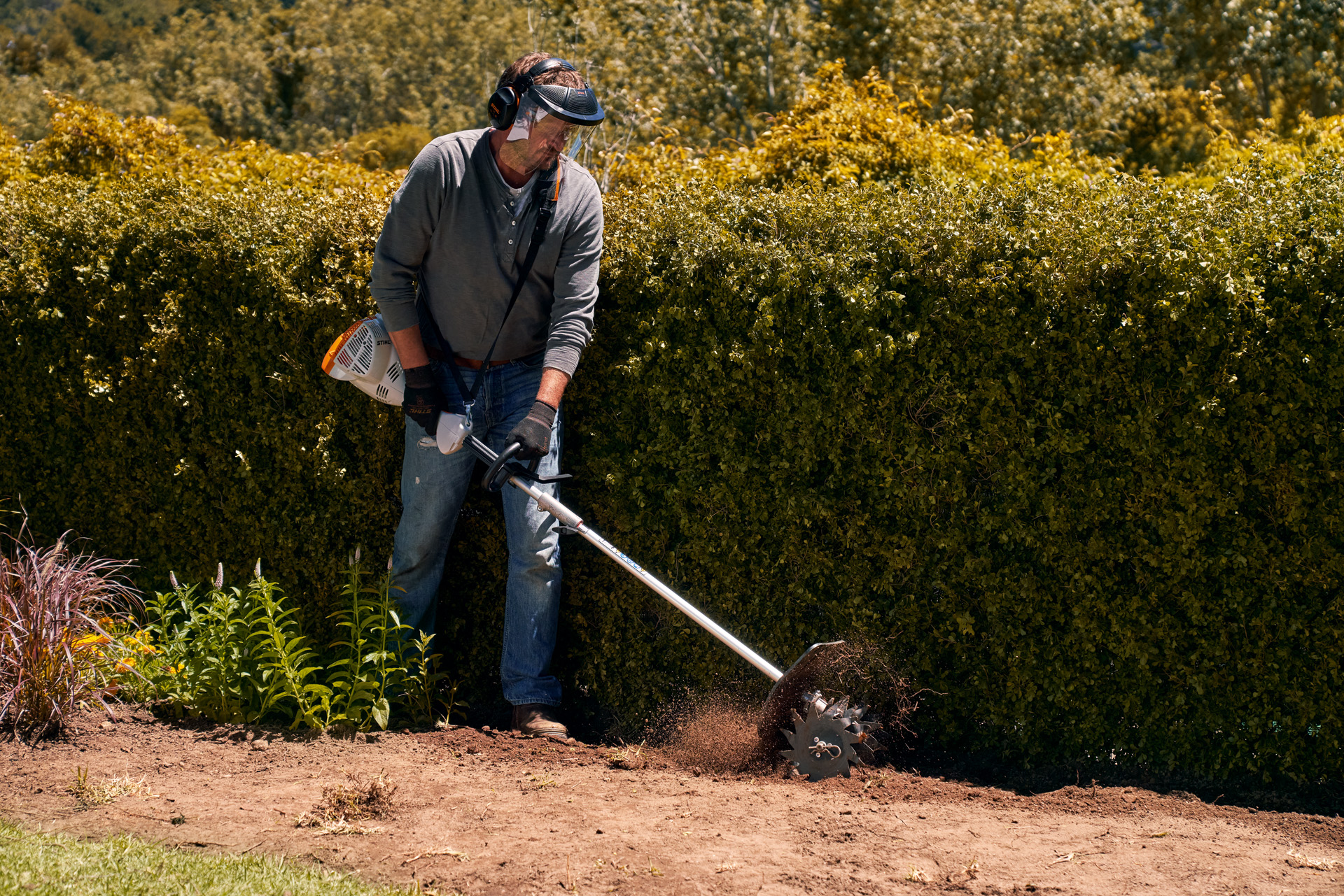 Homme portant une visière et des gants en utilisant le moteur combisystème STIHL KM 56 RC-E