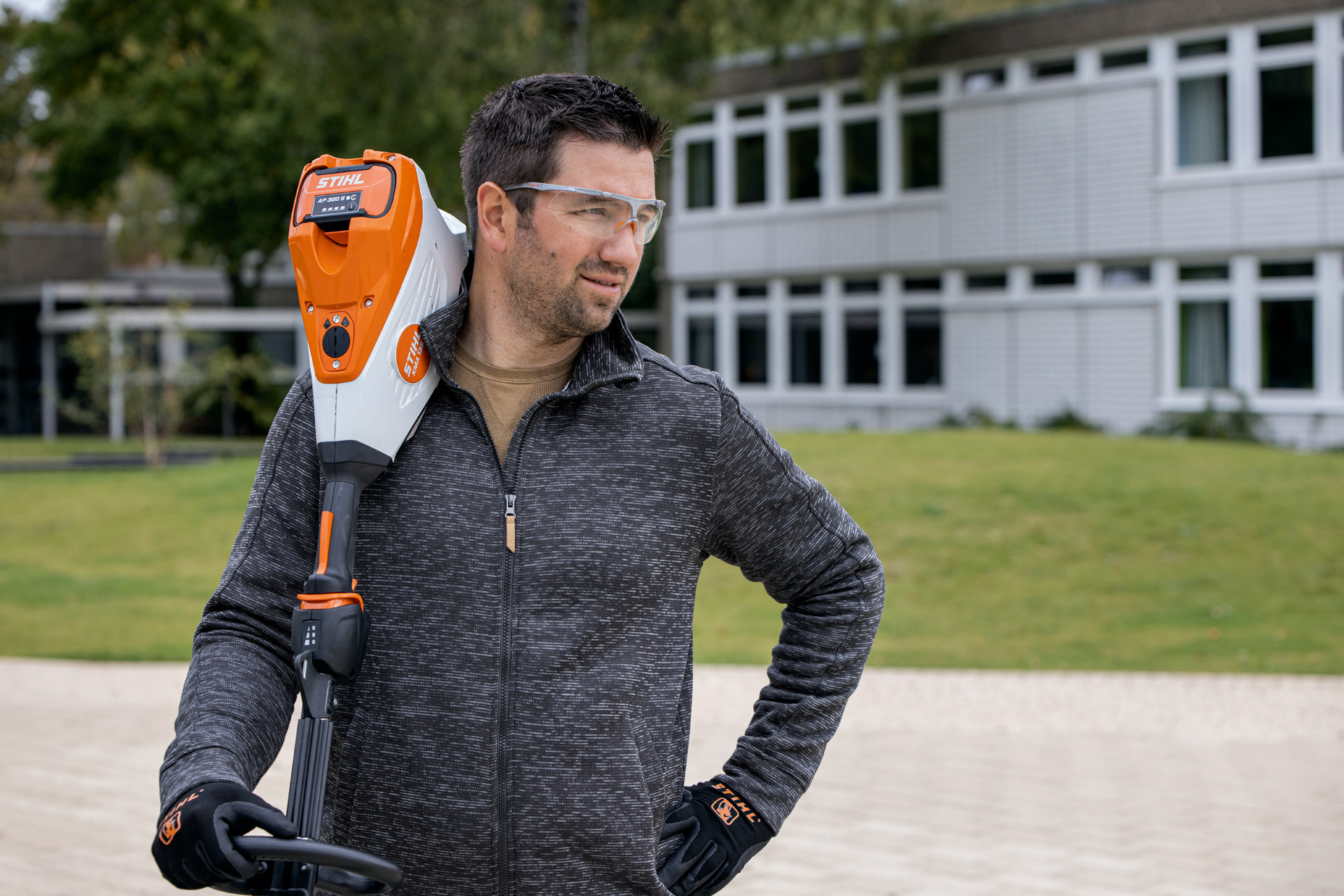 Homme avec un taille-haie à batterie STIHL HSA 94 devant un espace vert