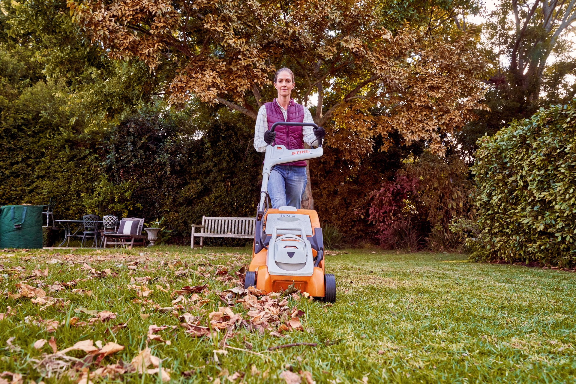 Une femme tond sa pelouse avec une tondeuse sur batterie STIHL RMA 339 C dans le cadre de l’entretien du gazon en automne