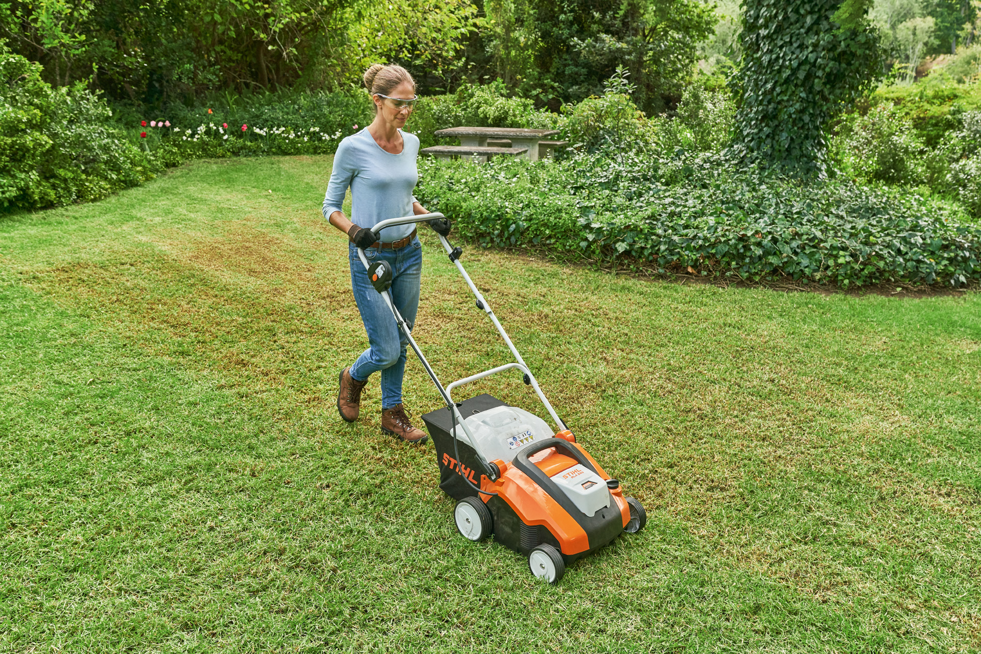 Femme avec lunettes de protection et gants de travail, utilisant le scarificateur à batterie STIHL RLA 240.