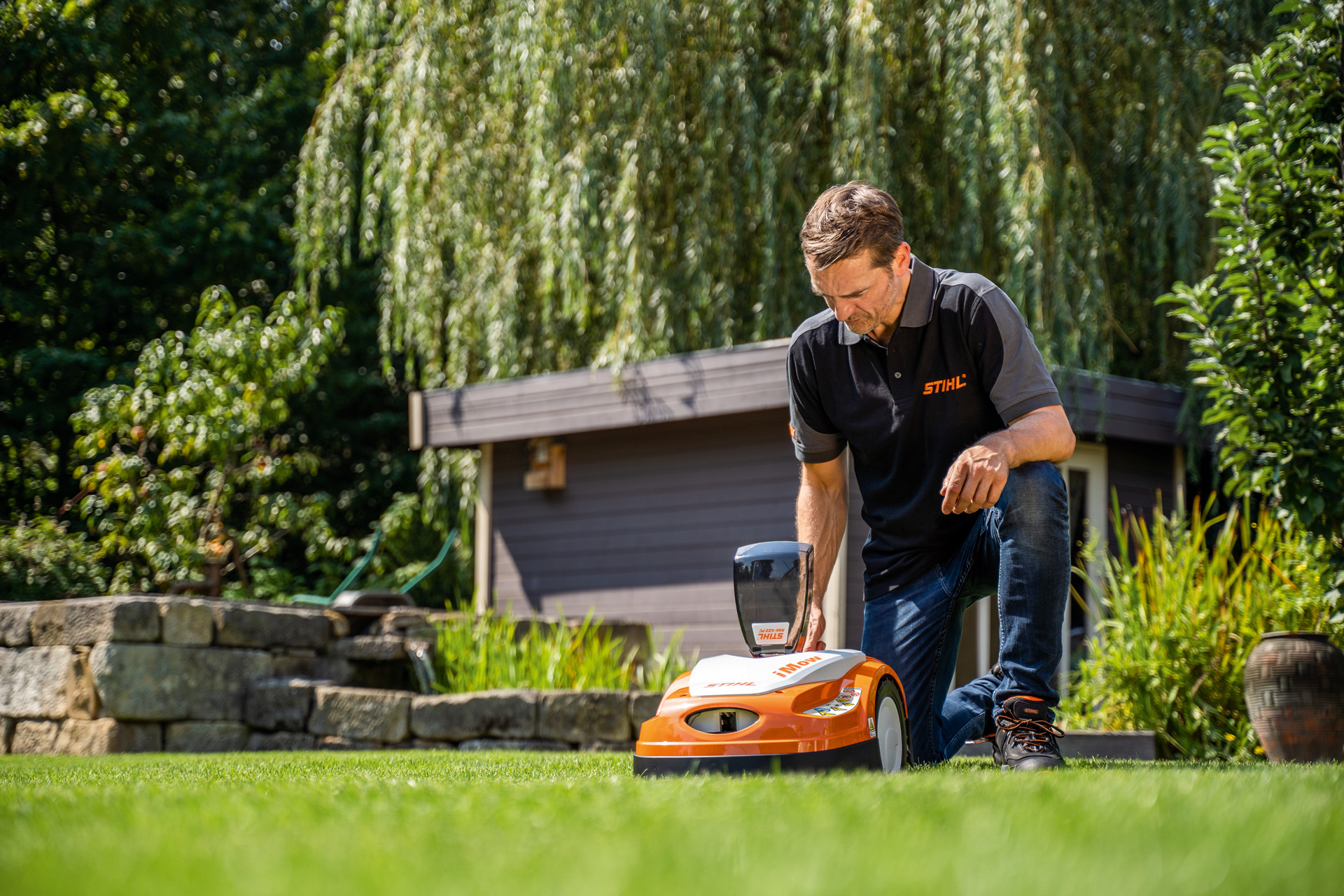 Un revendeur STIHL programme le plan de tonte d'un tondeuse robot STIHL iMOW dans un jardin.