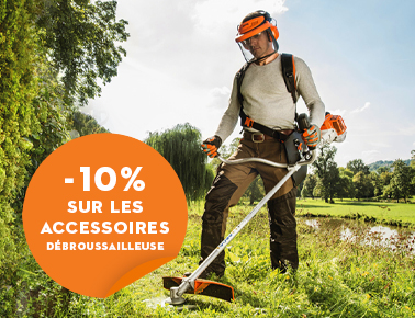 Un homme débroussaille un terrain preès d'un arbre