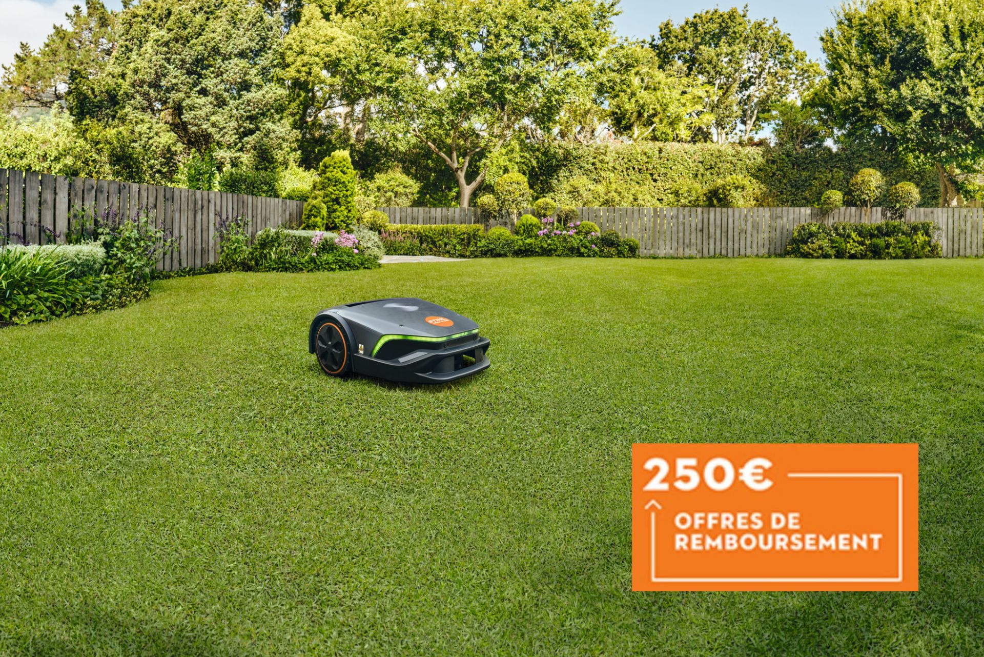 robot tondeuse Imow sur une pelouse verte dans un jardin entouré d'une palissade