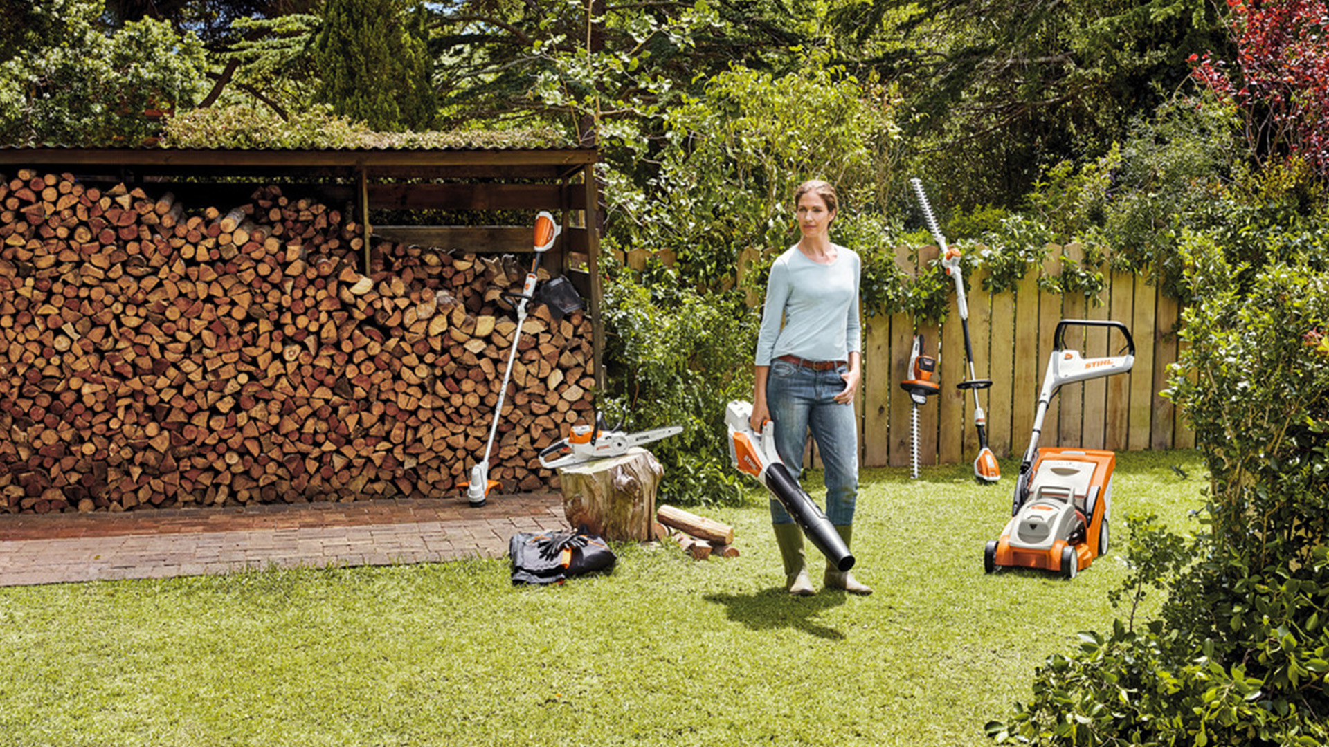 Une femme entourée d'outils de jardin à batterie STIHL