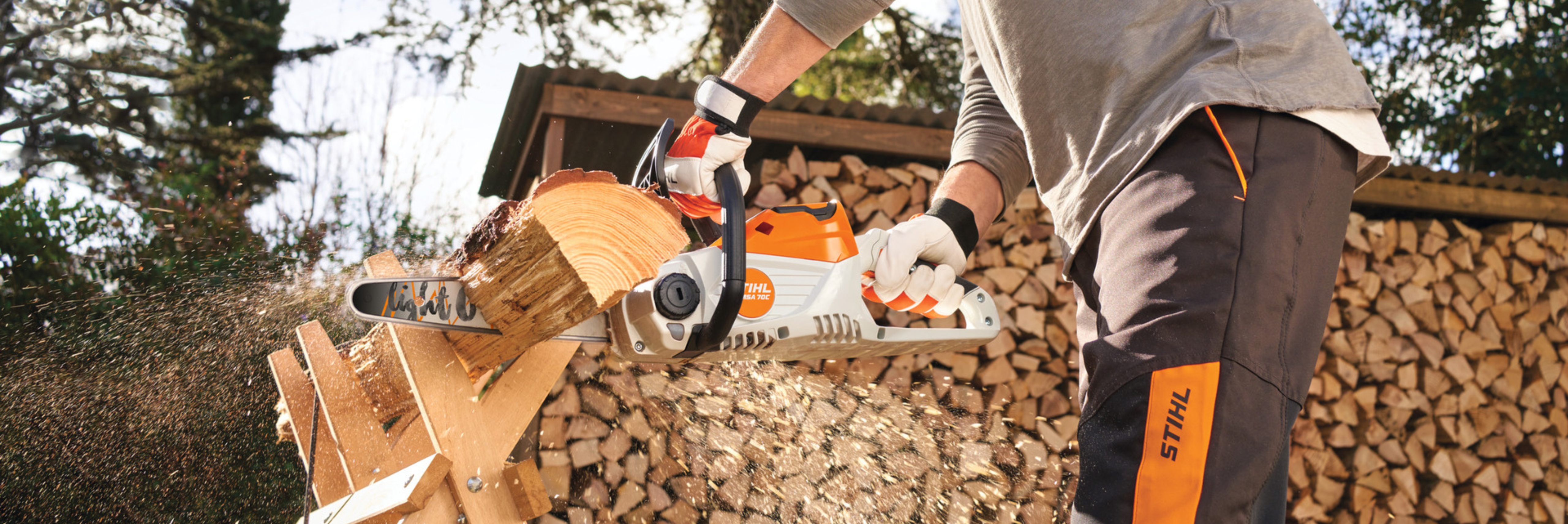 Un homme coupe du bois de chauffe avec sa tronçonneuse à batterie MSA 70 de STIHL