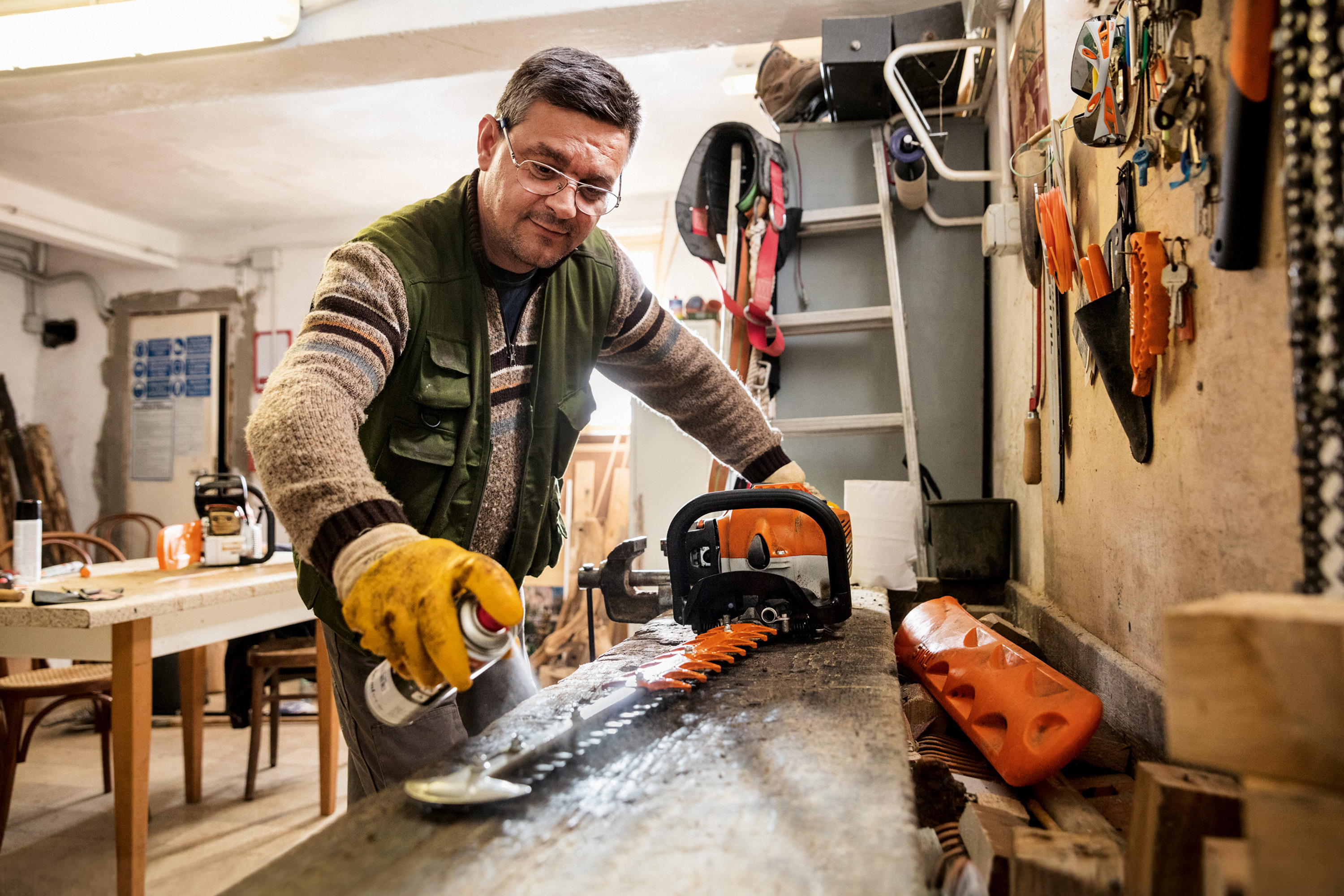 Un homme en train de vaporiser du detergent Varioclean STIHL sur la lame d'un taille-haie STIHL