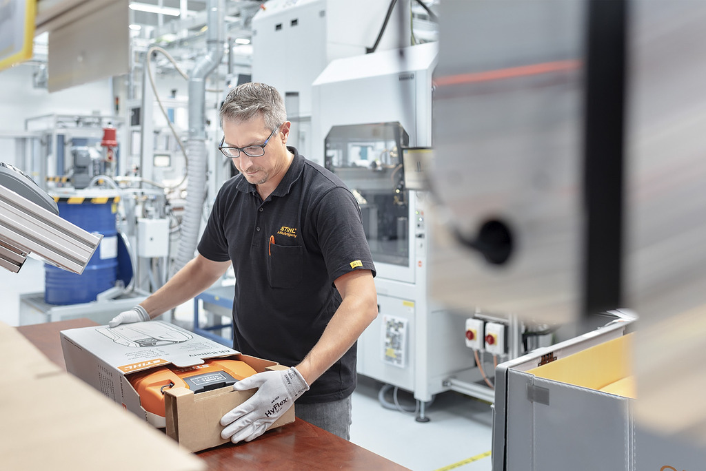 Un employé de la production de batteries met un outil sans fil STIHL dans un carton.