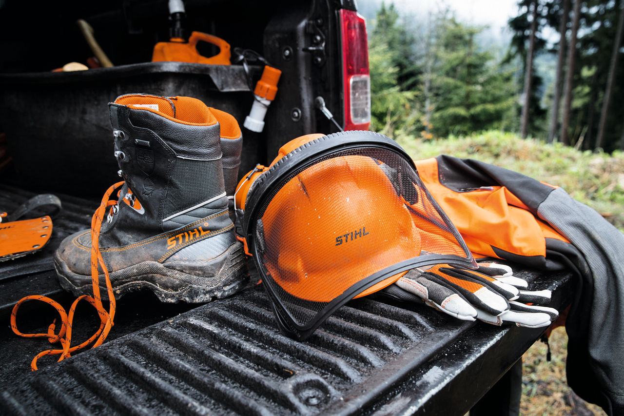 des chaussures de sécurité, un casque,; des gants et un des protections de jambes à l'arrière d'un pcik up