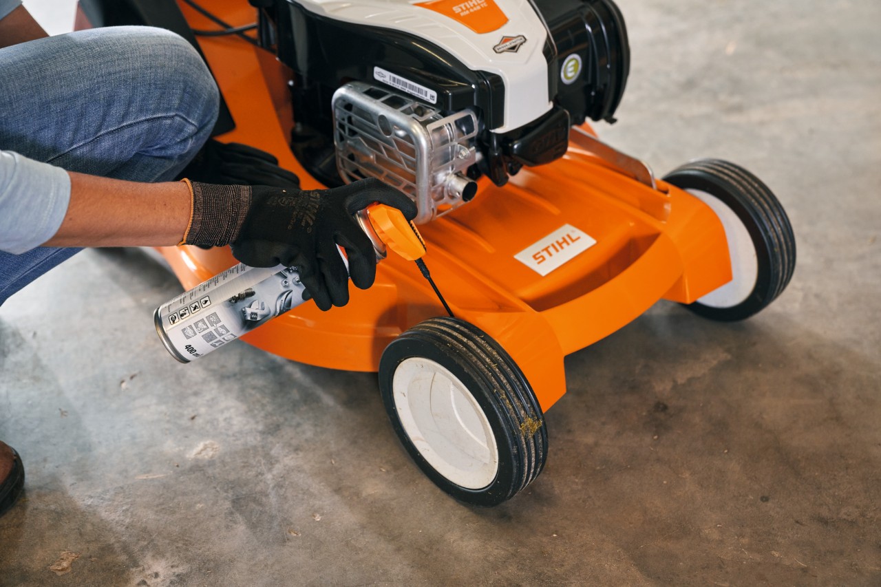 Femme rangeant sa tondeuse thermique STIHL RM 448 TC dans un garage