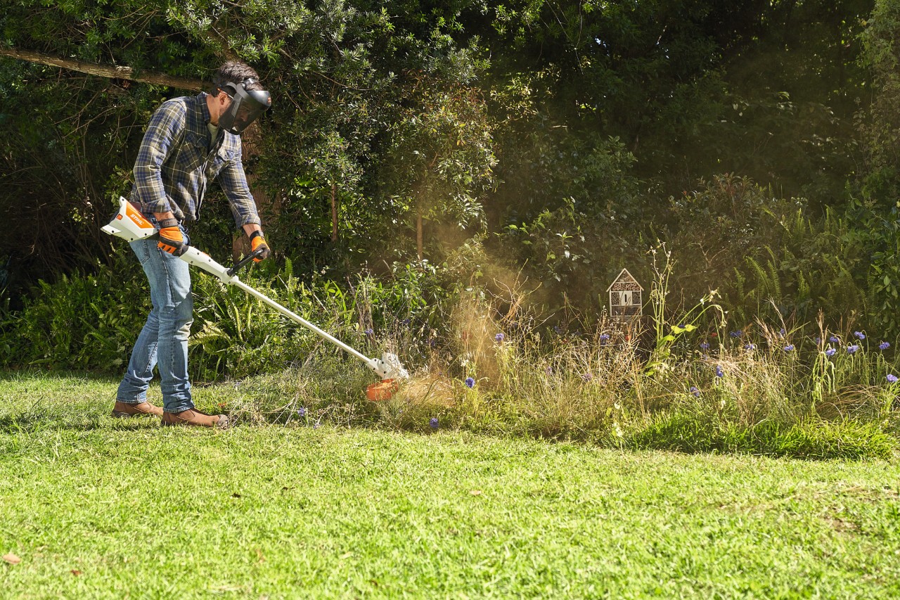 Homme débroussaillant une prairie de fleurs sauvages avec la STIHL FSA 57