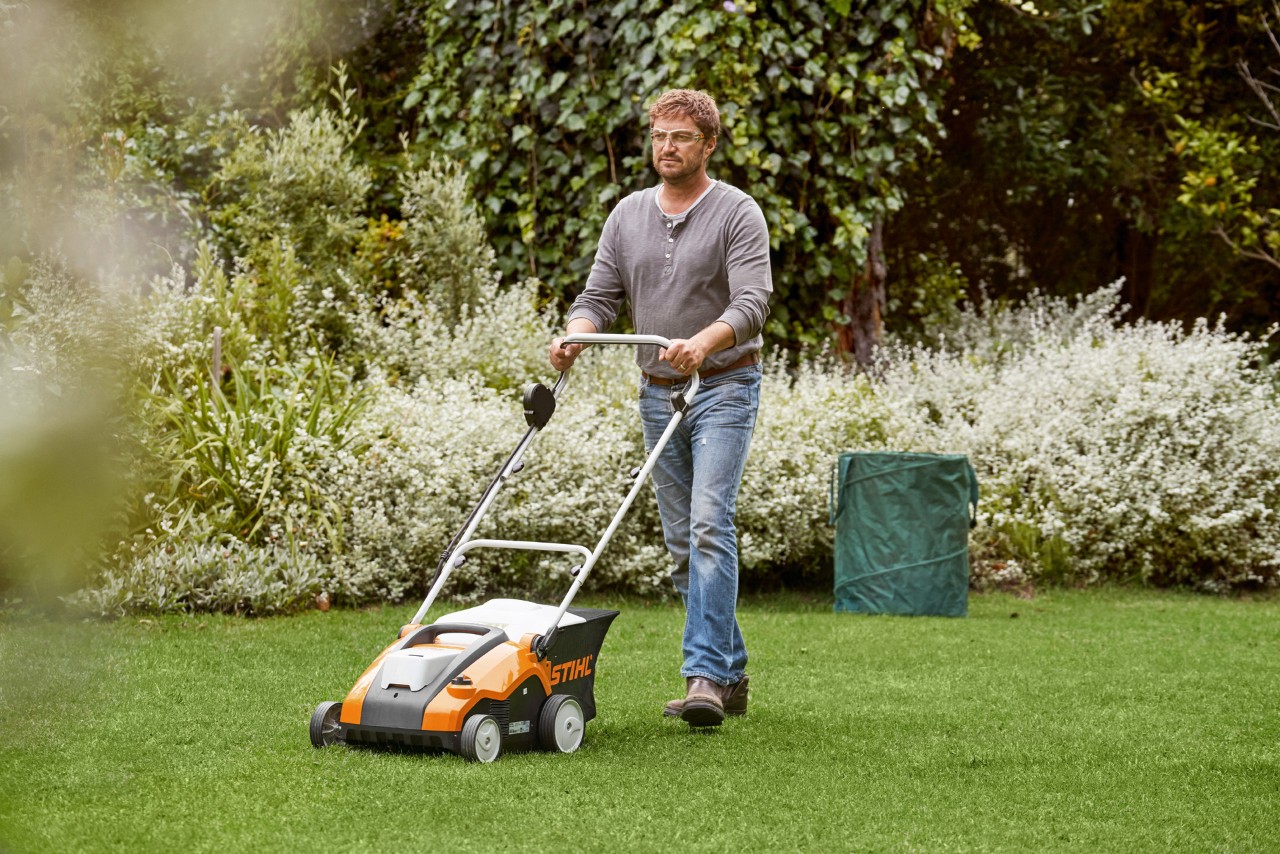 Homme réalisant le verticutage de pelouses vertes avec un scarificateur à batterie STIHL RLA 240
