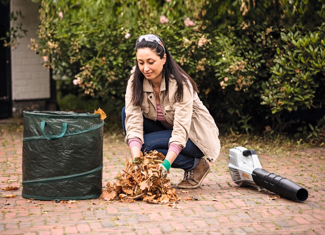 Femme enlevant des feuilles mortes à l’aide d’un sac et d’un souffleur STIHL BGA 56
