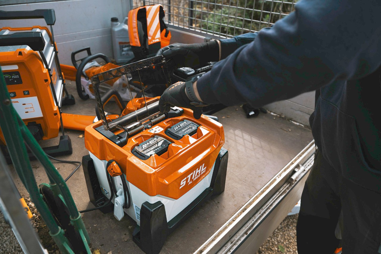  Le paysagiste place les batteries dans le chargeur pour les recharger.