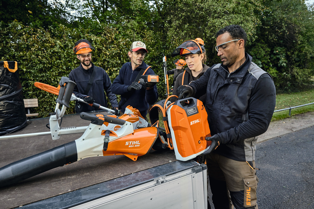 Une équipe de professionnels de l'aménagement paysager décharge son matériel professionnel STIHL à batterie de la zone de chargement d'un véhicule.