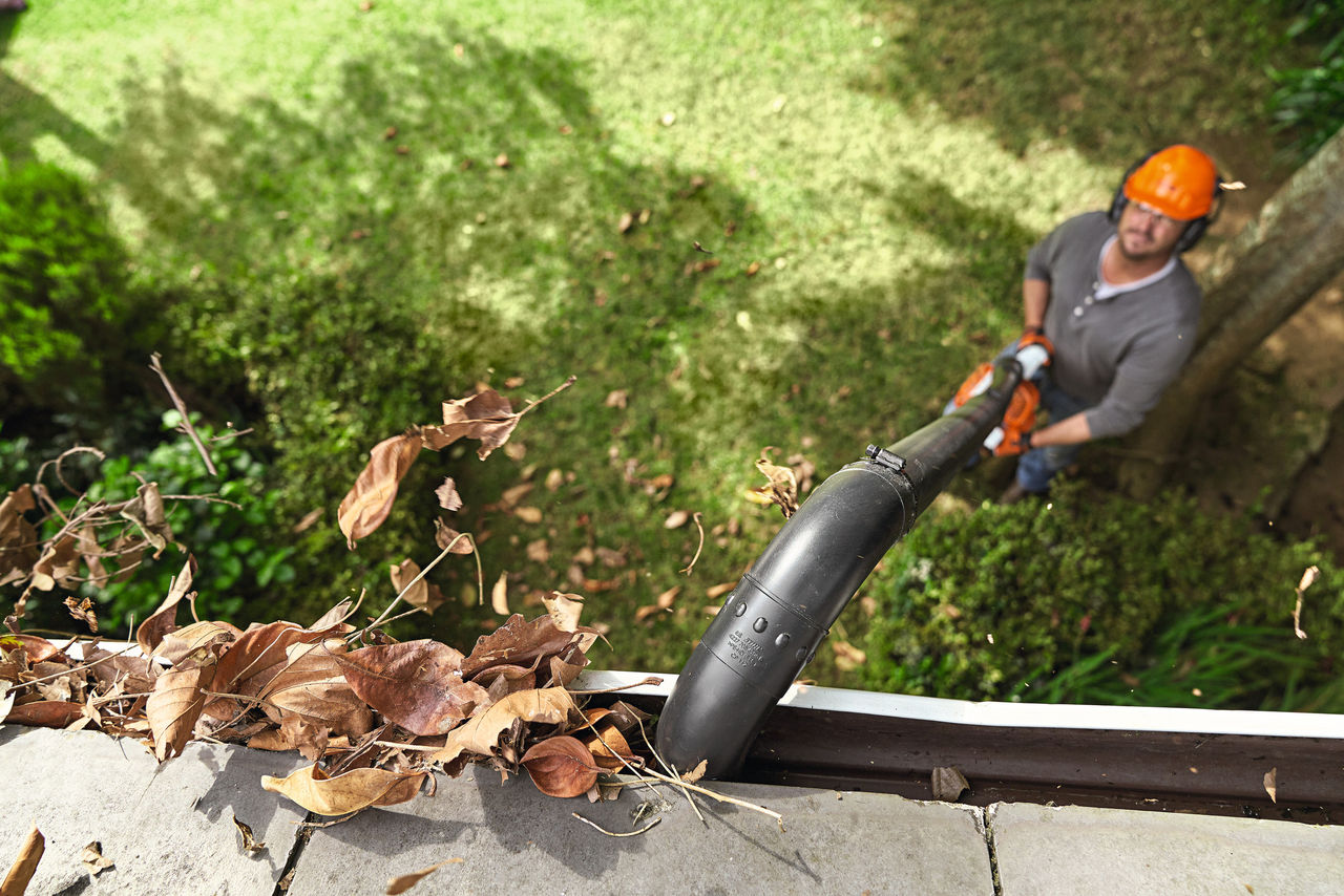 Homme nettoyant une gouttière avec le kit de nettoyage de gouttière STIHL