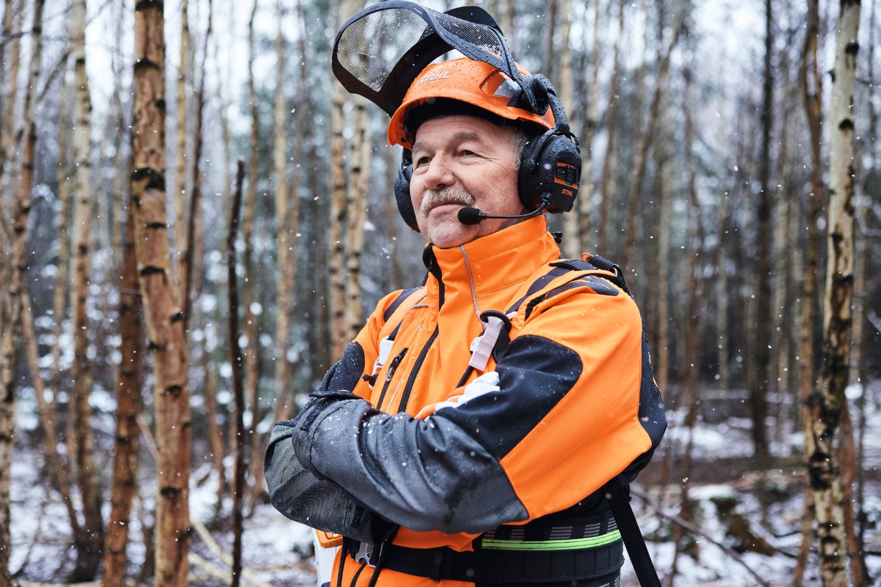 Martin Nolte, agent d’exploitation forestière, en vêtements STIHL, les bras croisés, dans la forêt