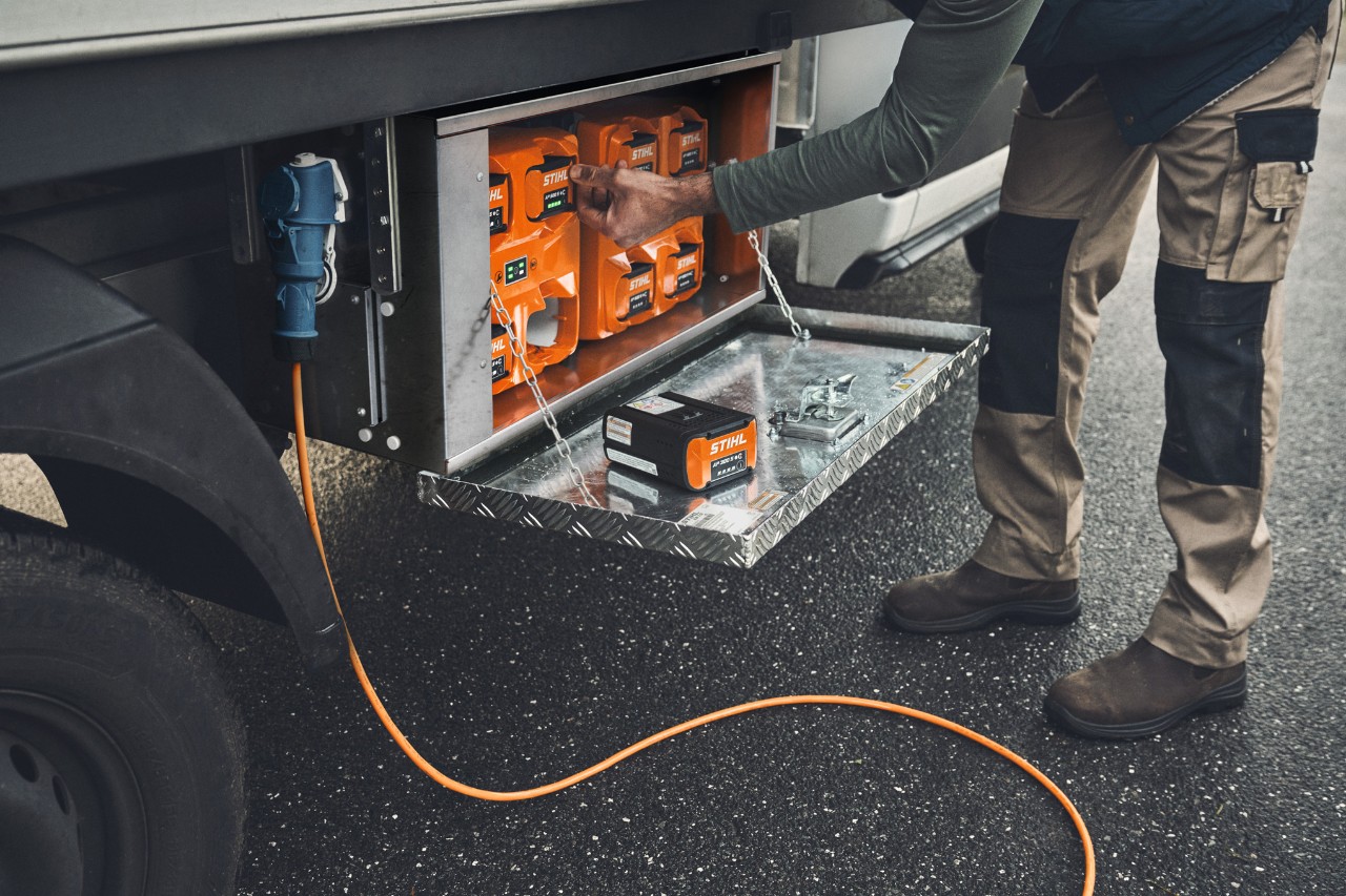 Un homme sort une batterie STIHL AP 500 chargée de la boîte de recharge 